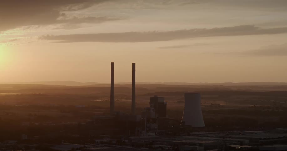 Two smoke stacks stand near a nuclear plant under a hazy sky