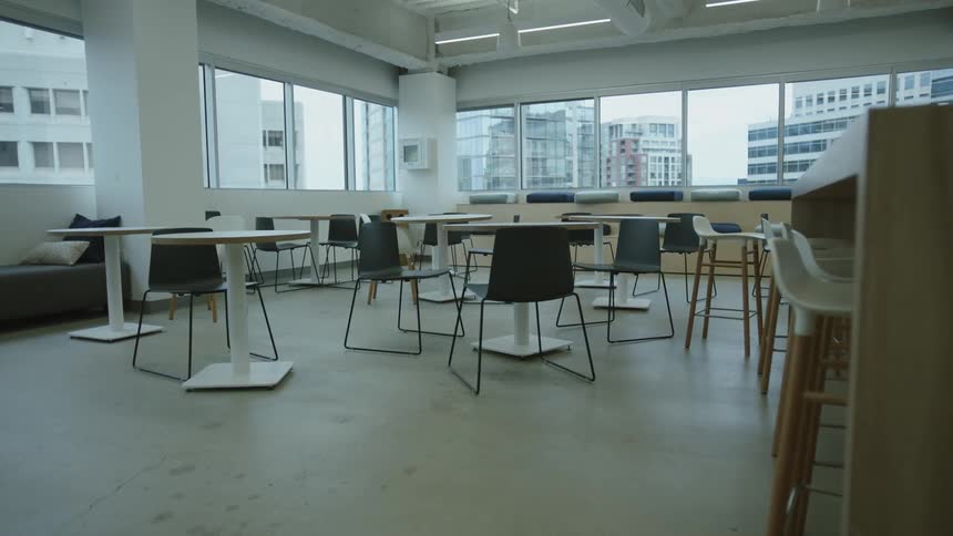 Tables and chairs in an empty restaurant with a view of downtown buildings