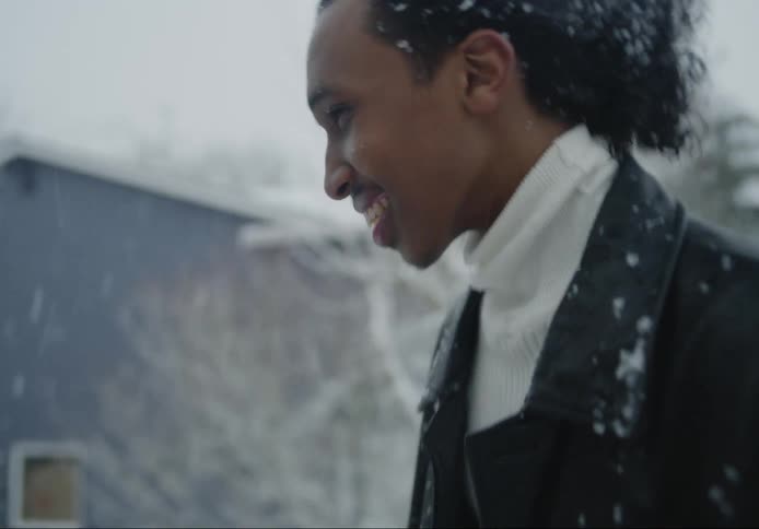 Two men are talking outside while it snows