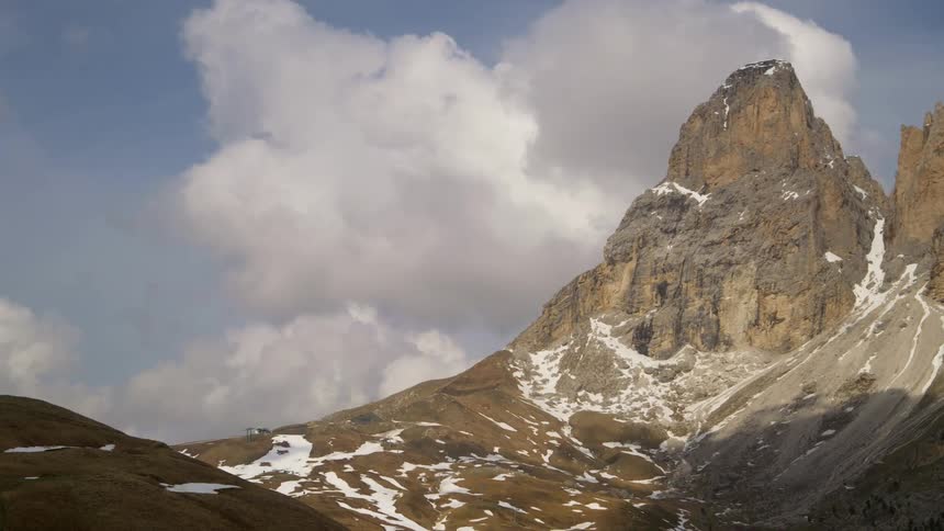 A mountain range peak with snow in the ridges on a bright and cloudy day