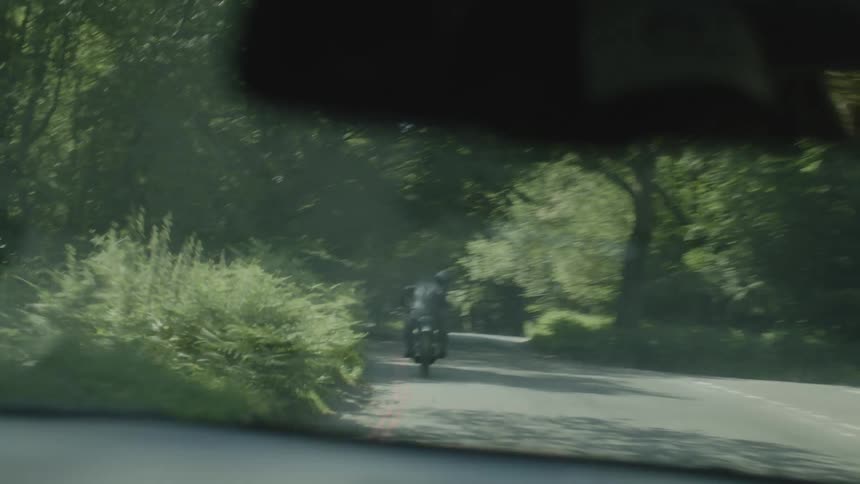 A car is following a motorcycle on the road