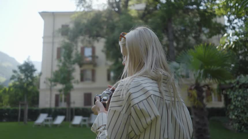 A woman taking photos from a digital camera in a tree environment