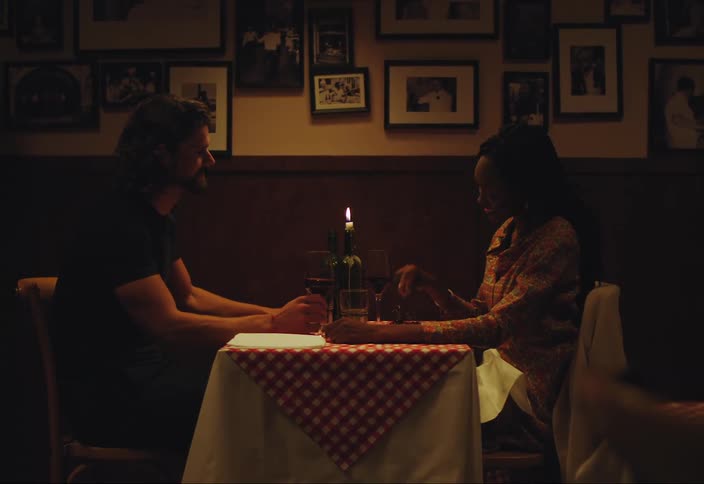 Man and woman sitting by the table in a restaurant taking and holding a wine glass