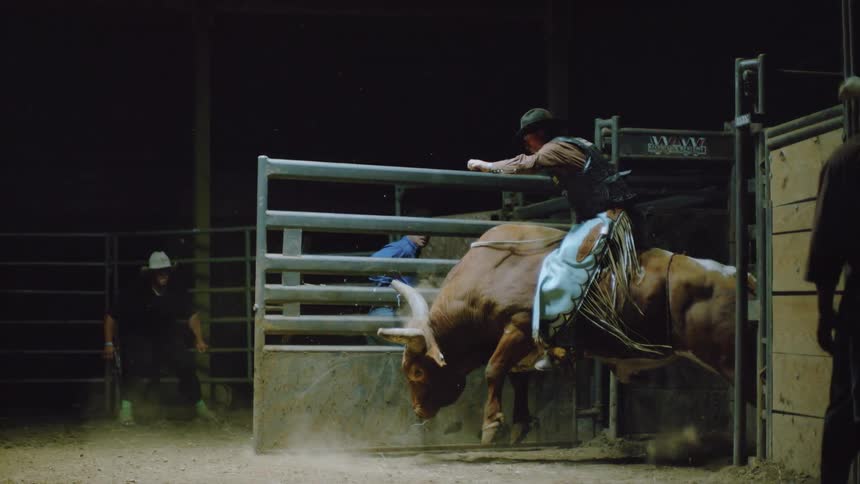 A rider storms out of a gate on a bull