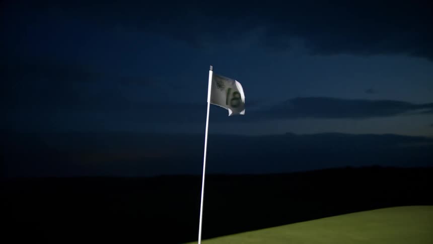 A flag on a golf course with the number 18 is moving in the wind