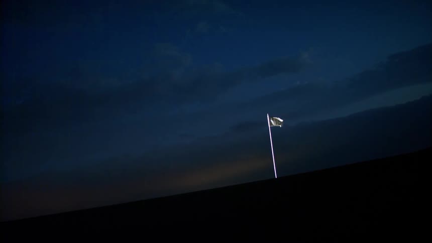 White flag moving with the force of the wind in an outdoor setting at night