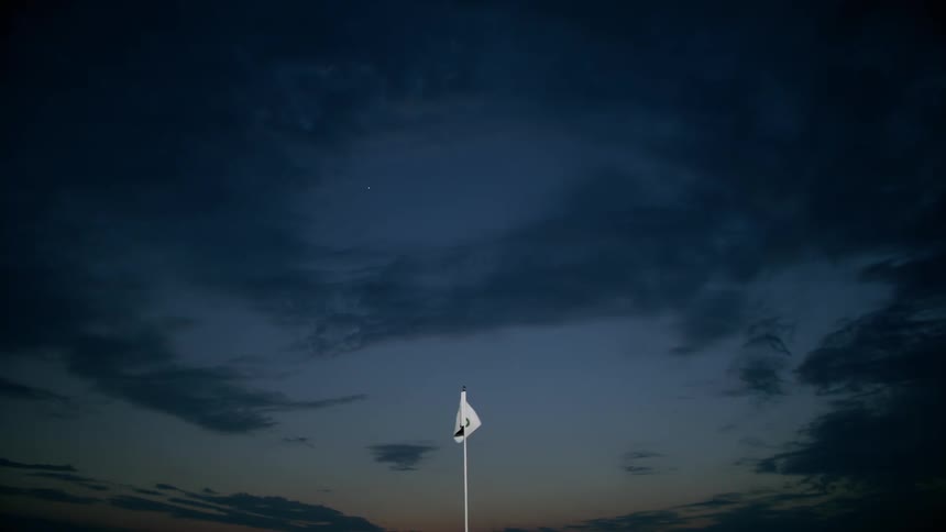 Eighteenth hole flag waves against night sky