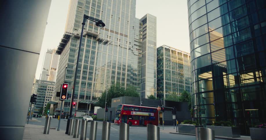 Red doubledecker bus drives by skyscraper downtown