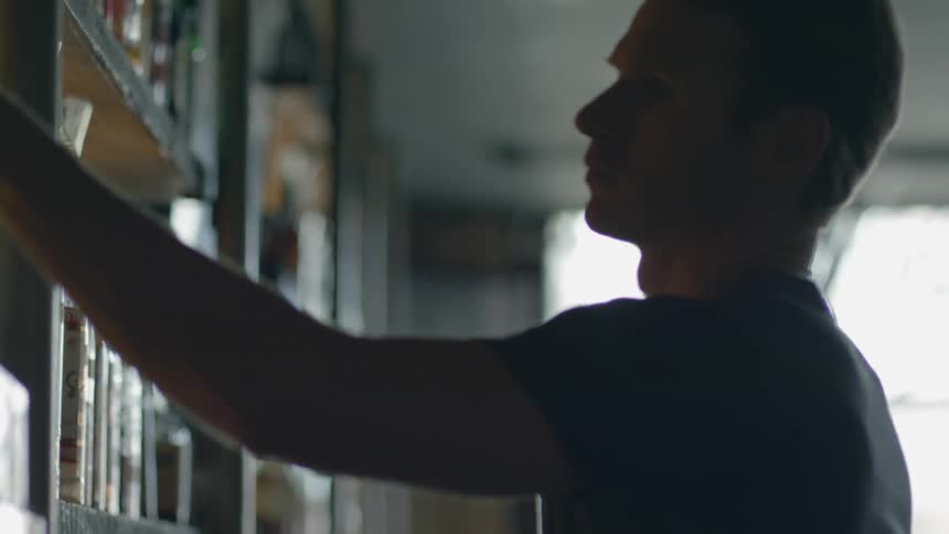 A man reaches on a shelf in front of him