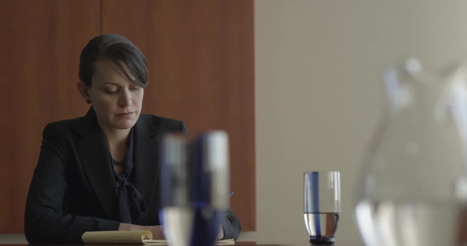 A woman sits at a table looking at a notebook