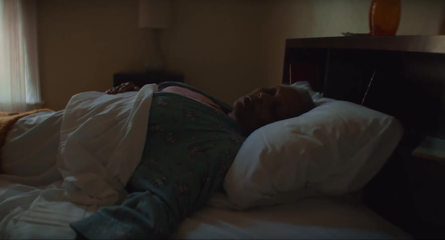 Elderly woman resting in bed on a dimly lit bedroom