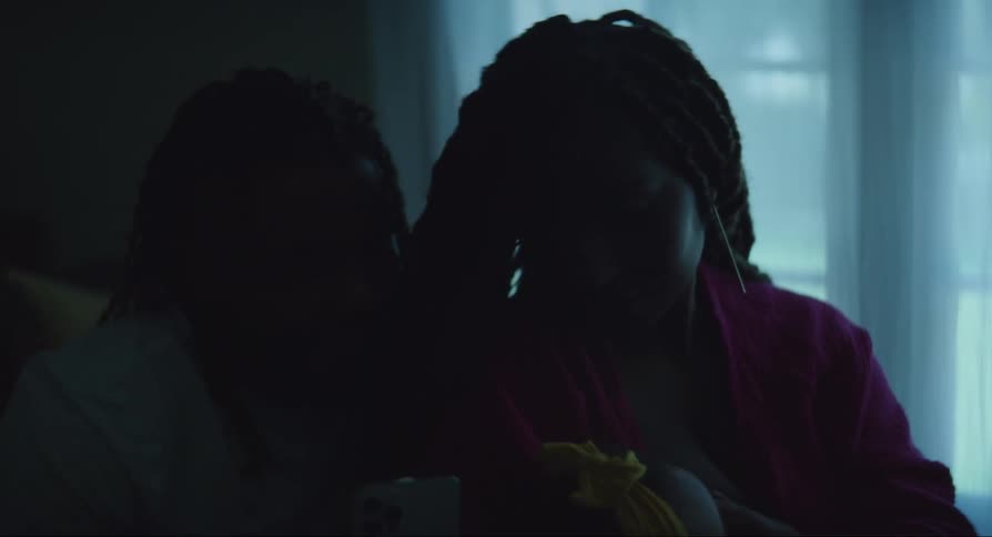 Mother breastfeeding her baby with her husband beside her holding a cellphone