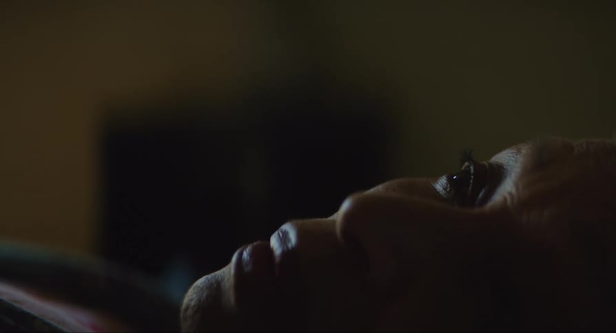 An elderly woman in bed stares at the ceiling
