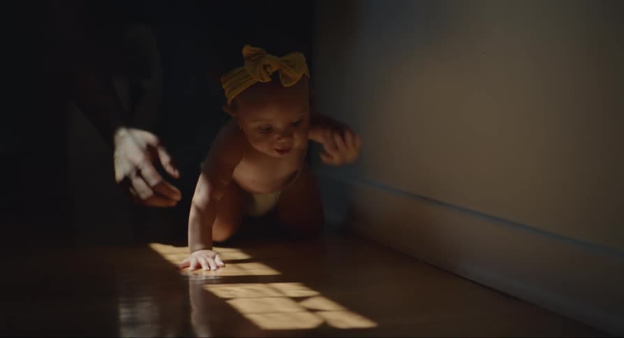 Baby crawling on the floor with a human hand assisting