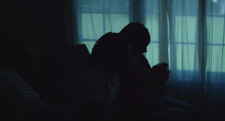 A small family sits in a dark room