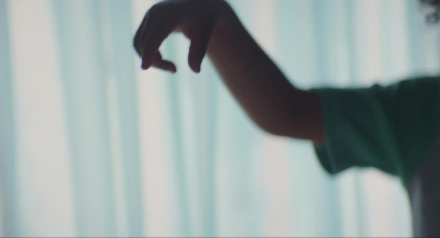Black male child standing up indoors holding a golden wristwatch and then dropping it from their hands during day time
