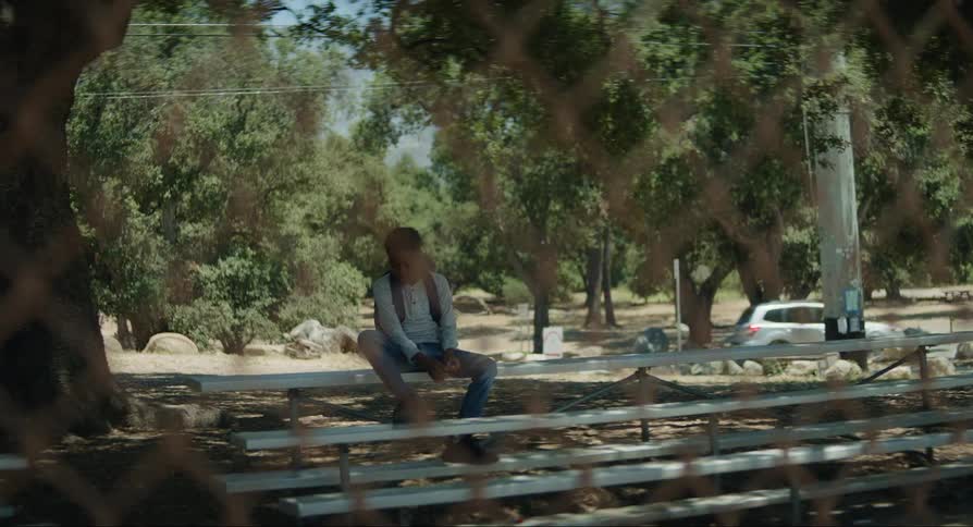 Boy sitting on a small bleacher playing with his hands