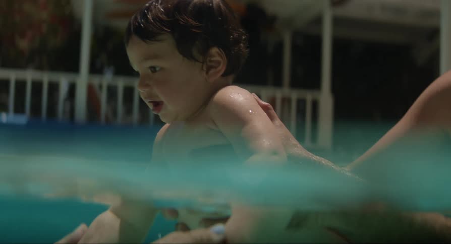 Parents holding their baby son in the pool and playing