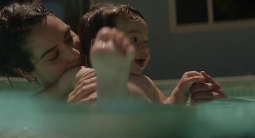 A small family is swimming in the pool on a sunny day