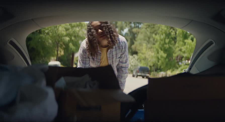 Man loading boxes into the trunk of his vehicle and closing it