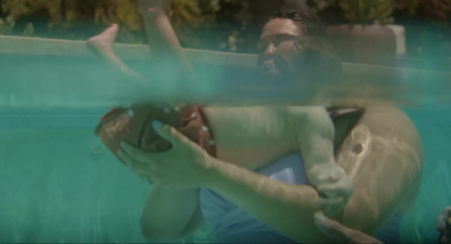 Parents inside the pool playing with their baby son