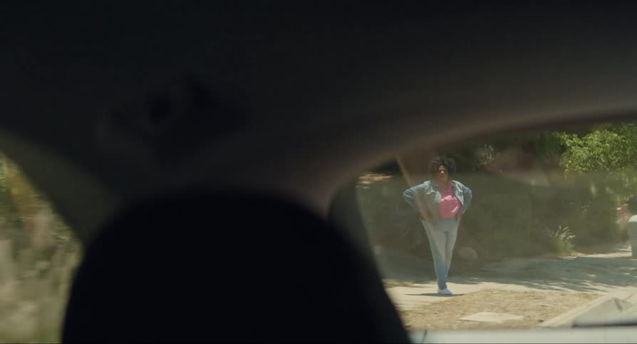 Camera from inside a car observing a woman as the car moves the woman looks places her hands on her waist and observes