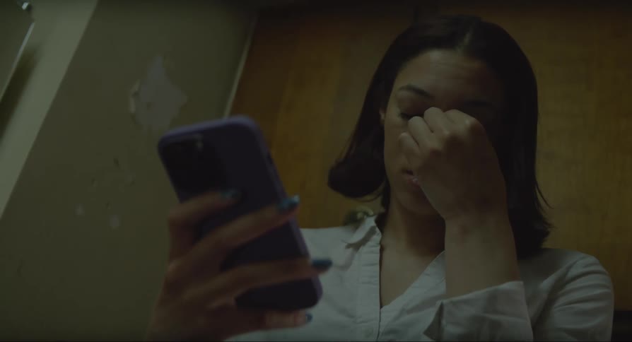 A young woman is on a cell phone and raises her hand to her face