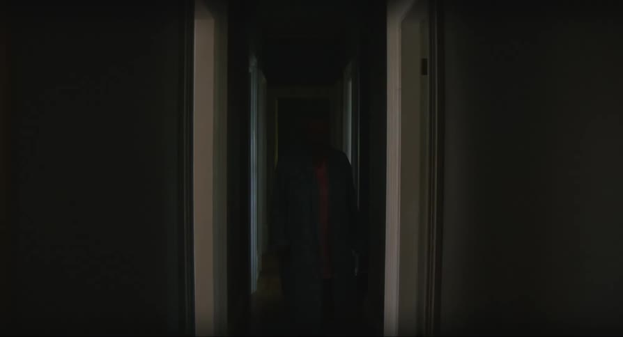 Woman wearing robe blocks down dark hallway through door