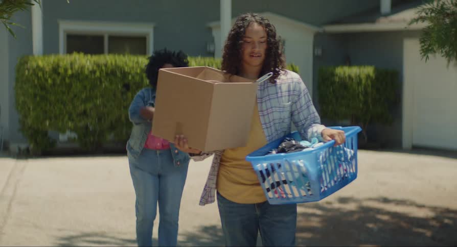 Woman helps son carry box to car outside house