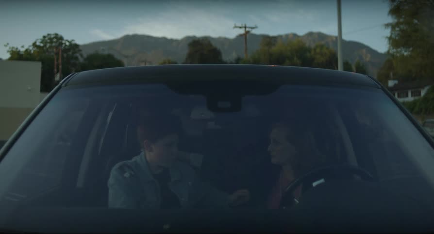 A mother hugs her son in the car