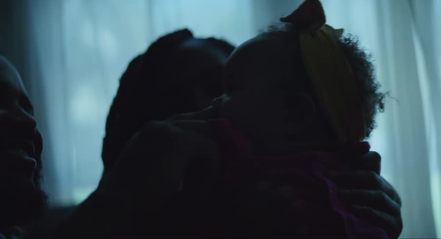 Parents sitting in a dark room and playing with their baby daughter