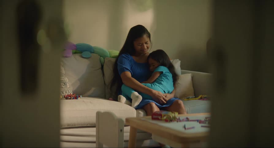 A mother cradles her daughter on the couch