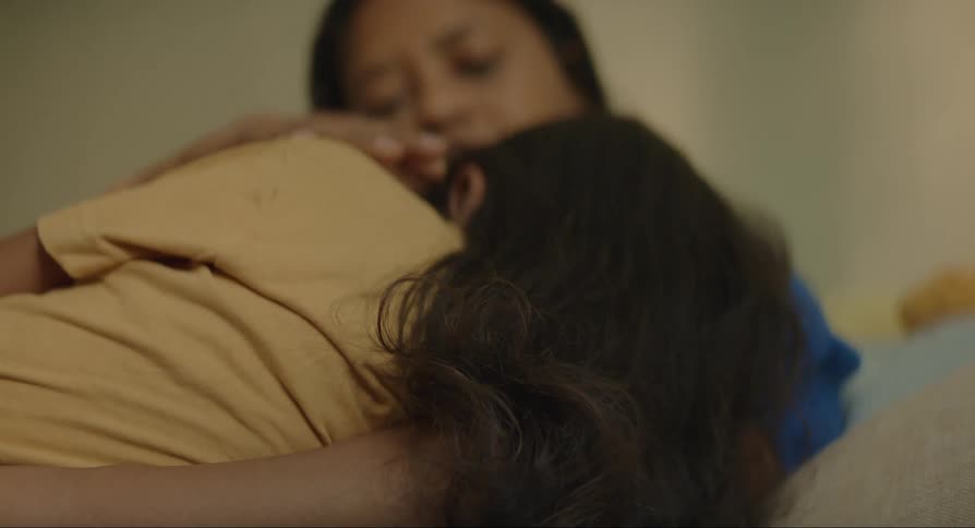 A mother stroking her daughters hair while she sleeps