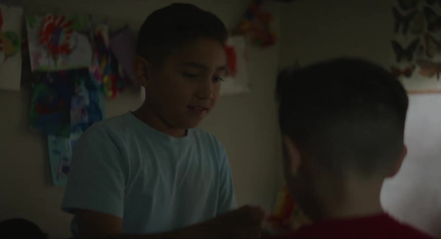 Children play with each other in a room with paintings