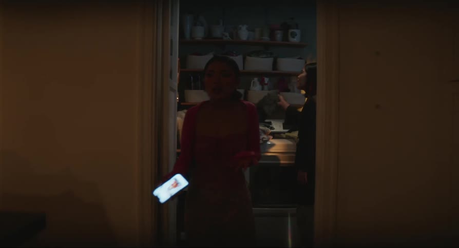 Woman holding a mobile phone on her hand arguing with another woman folding clothes