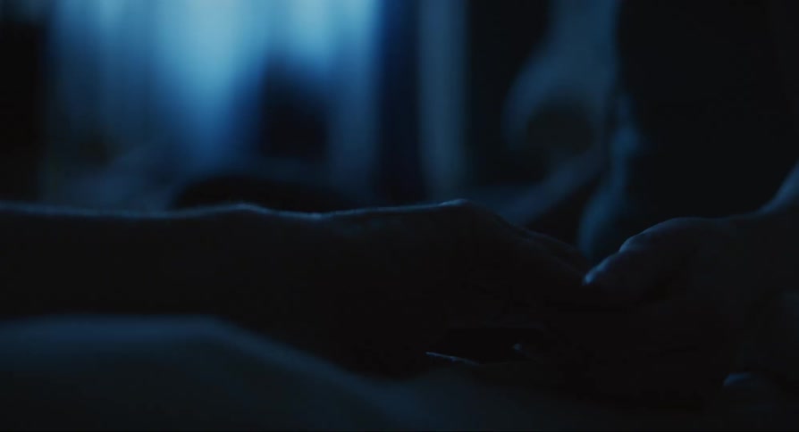 Two hands caress in dim room