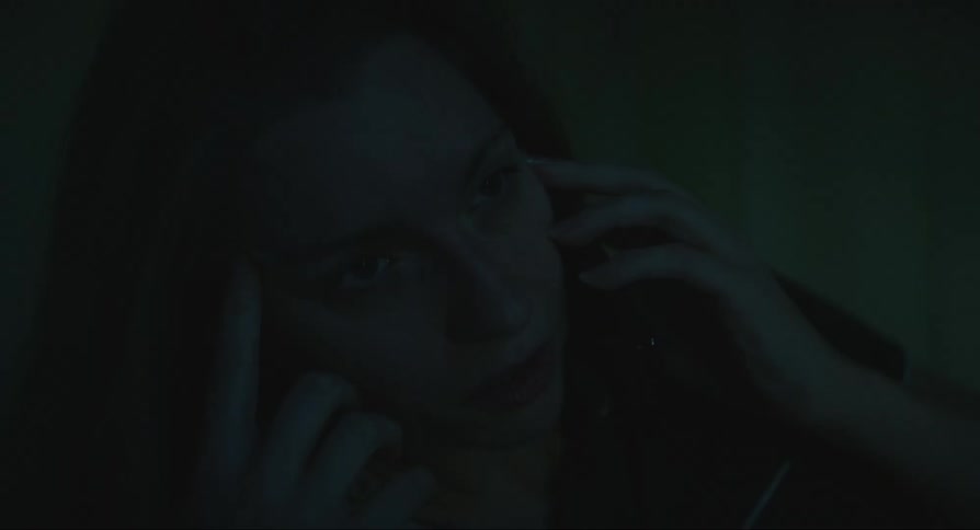 Woman talking on her cell phone lying on the bed in a dark room