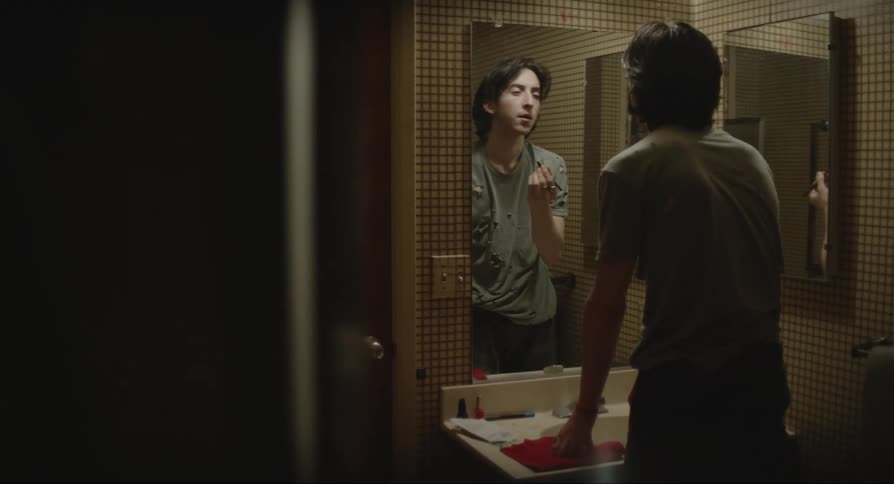 Man facing the mirror and applying makeup