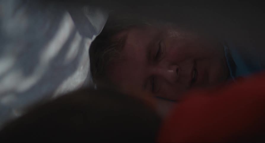 Man lays on side under sheet talking to someone
