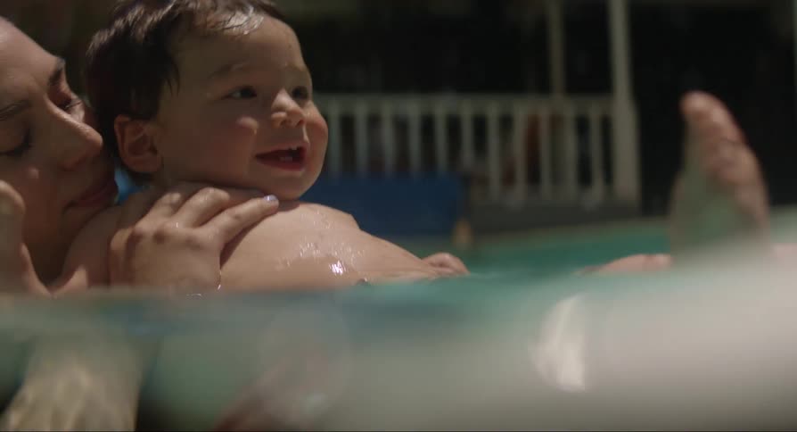 Baby and adults interact in pool