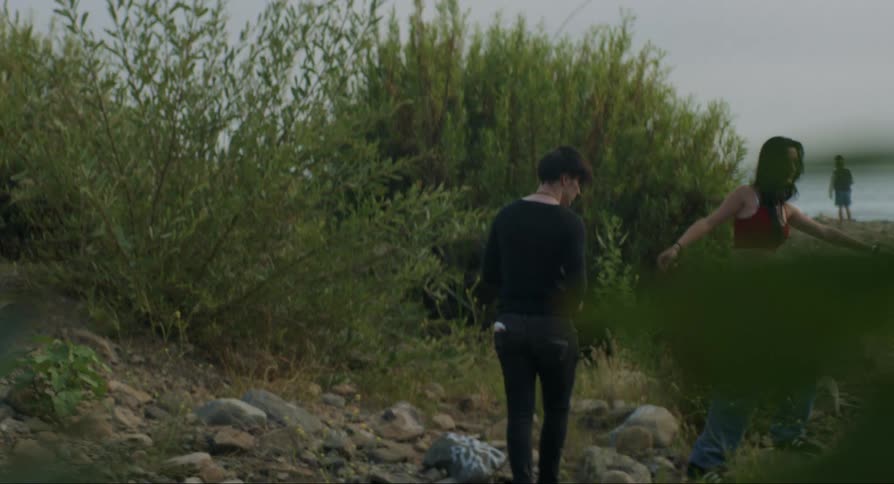 A young man and woman walking towards a beach
