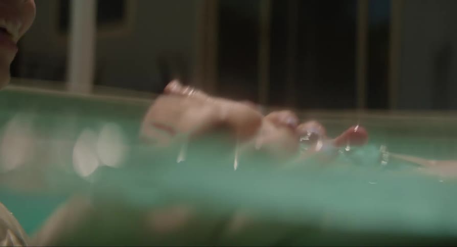 A man and woman holding and kissing a baby in a bathtub