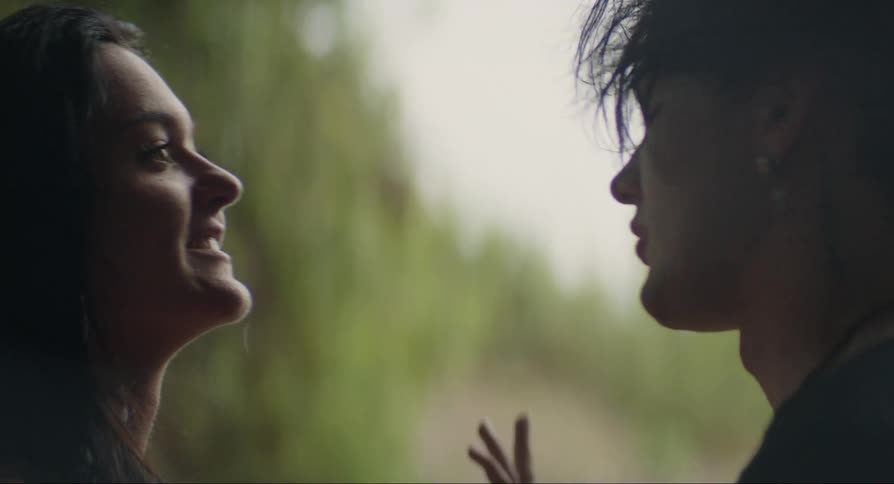 A young girl and boy standing together as the girl kisses the boy on the cheek and they talk