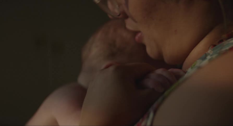 A woman hugging a baby is cuddling and talking to him