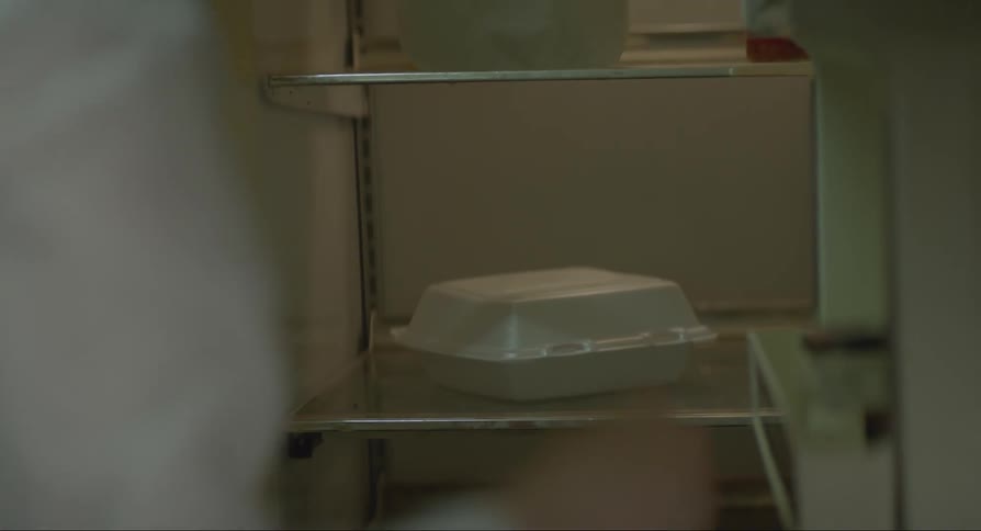 A woman opening the fridge and looking at the food