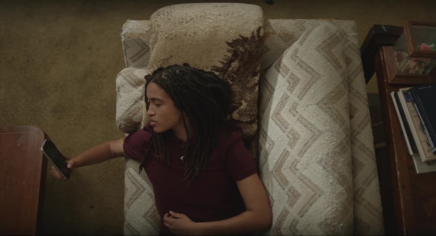 A young woman laying on a couch while her phone rings she picks it up and puts it back down