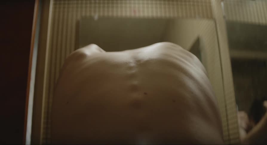 Tshirtless and extremely thin man looking at himself in the mirror