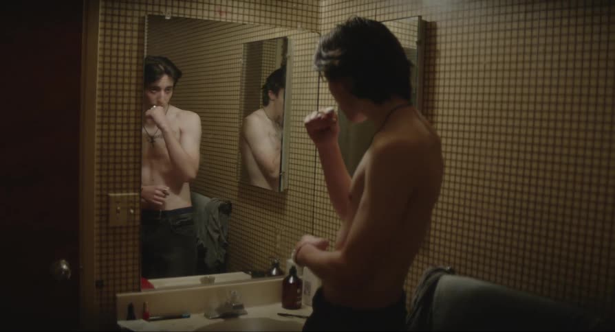 Man plays around posing and acting while staring into bathroom mirror