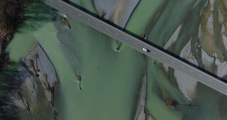 Topdown aerial of a car crossing a bridge over a swamp