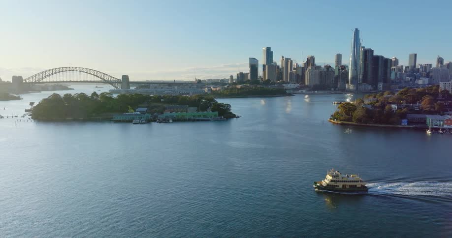 An aerial view of a city with an island and a boat sailing across the sea